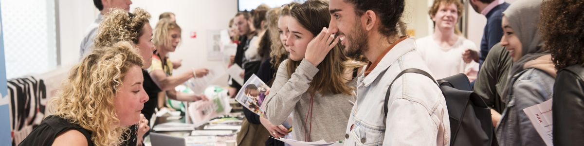 Afbeelding met studenten die een informatiepakket ontvangen